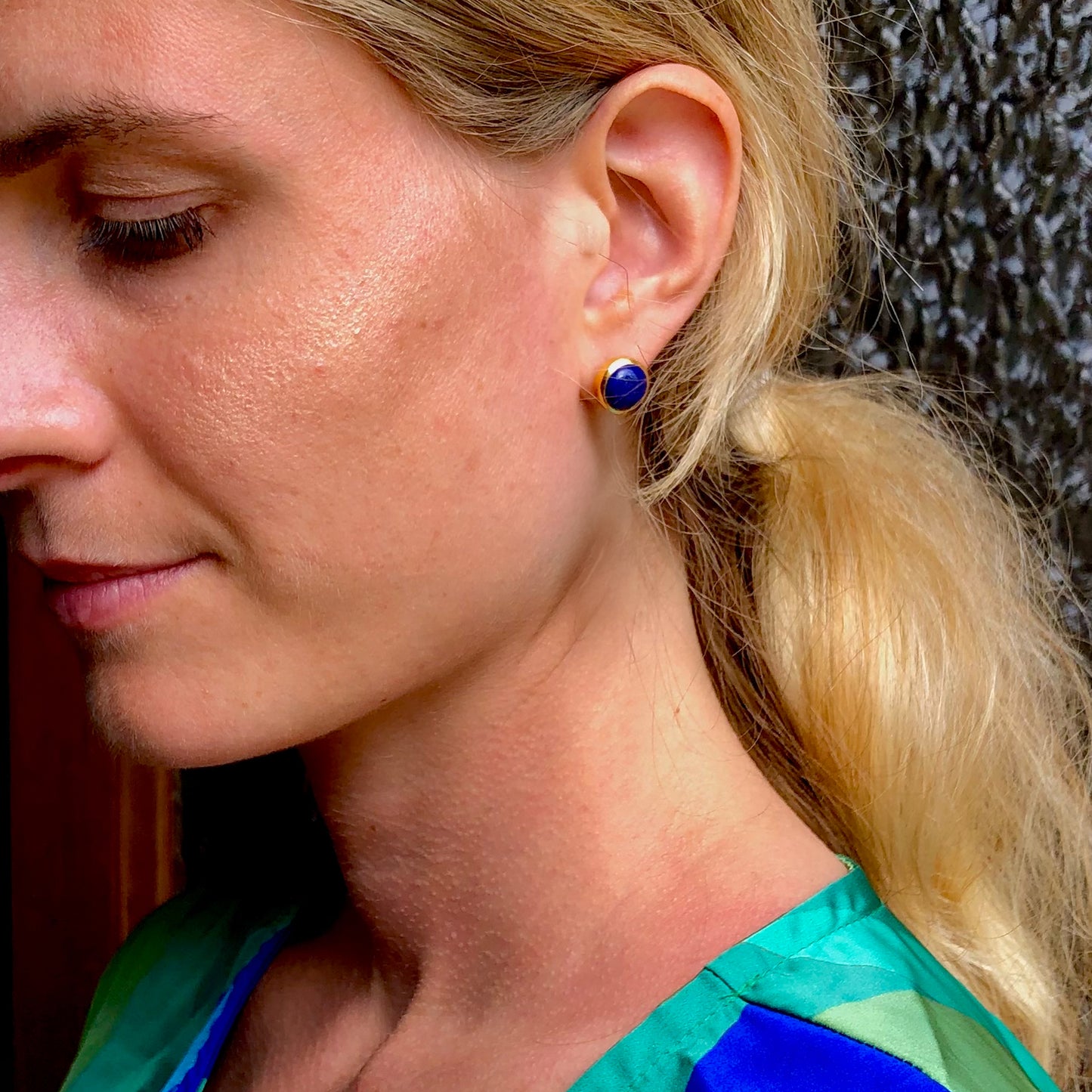 Close-up of a woman wearing blue lapis lazuli stud set in yellow gold