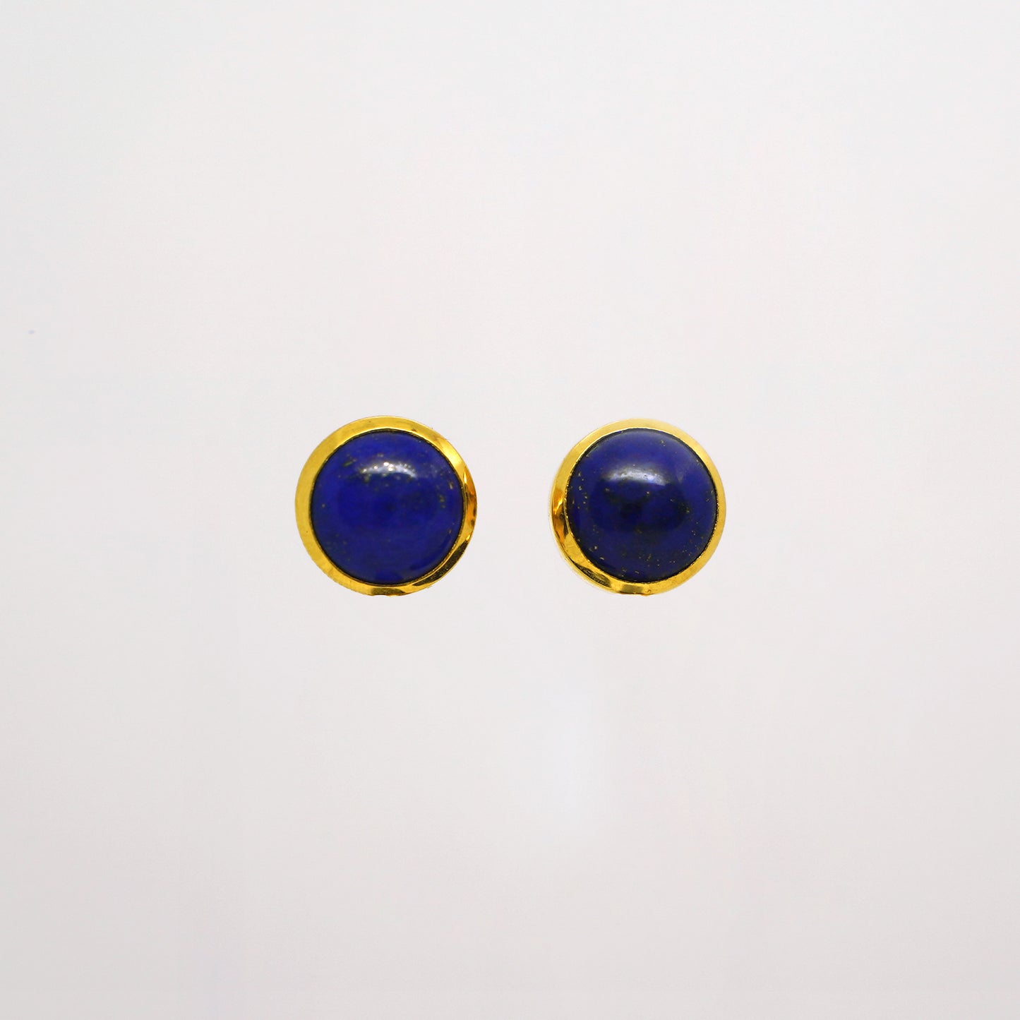 Pair of round blue lapis lazuli studs with gold rims on a white background